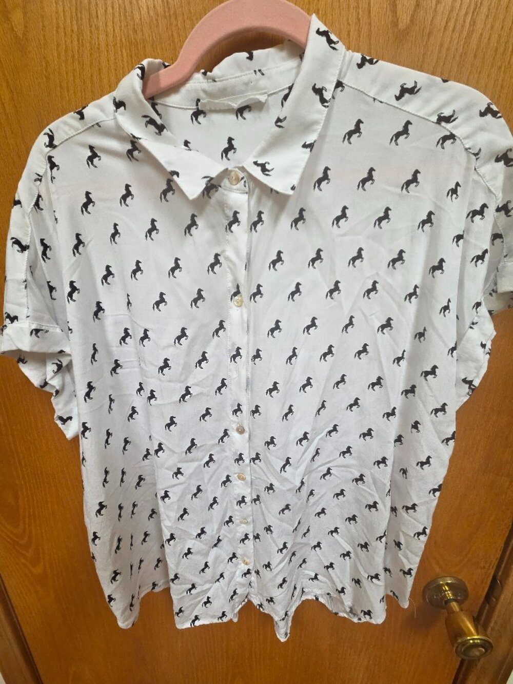 white short sleeved button down shirt with a repeated horse print pattern